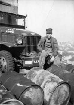 Bert Crowson sitting on a military truck and drums
