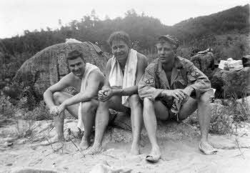 Three of soldiers sitting on sandbed
