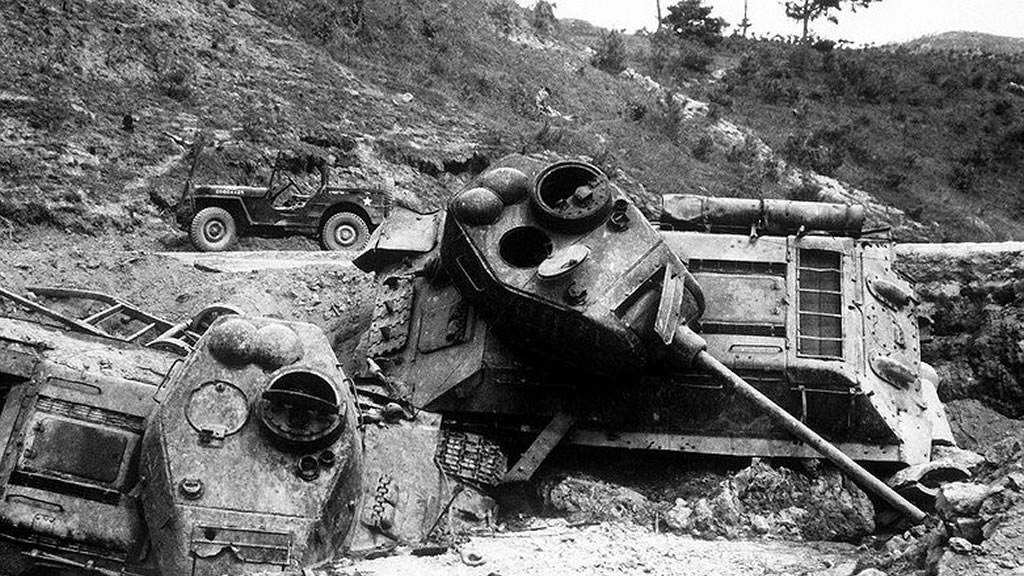 tank on its side after being bombed, jeep in background