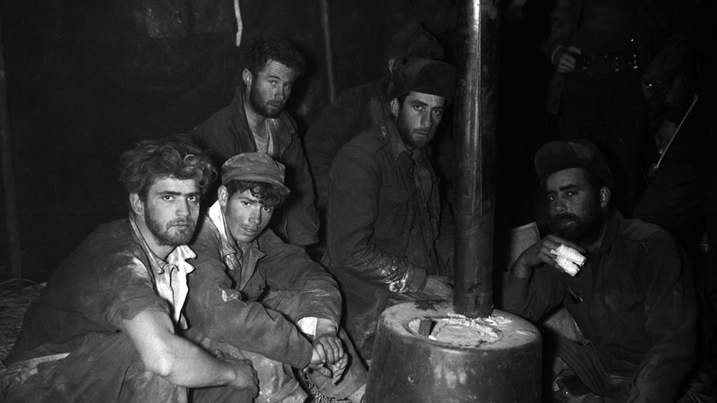 group of bedraggled soliders around barrel stove