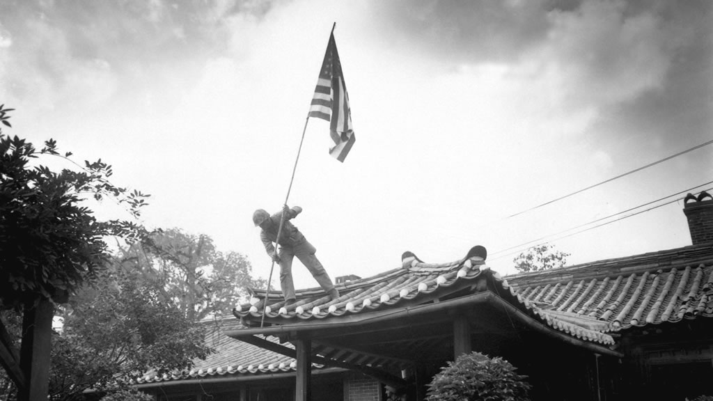 solider hoisting US flag on roof of building