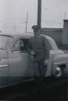 Edward Grala in his uniform by a car	