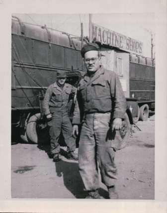 Two soldiers in front of machine shops	