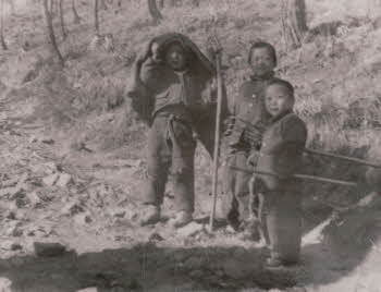 Three Korean boys holding farming tools