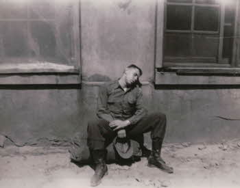 A solider taking a nap leaning on wall
