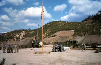Jeep of Chaplain, Peter Doyle, Vandyke being set up a shelter for mass, flag pole, hills