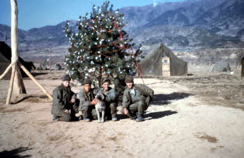 Co. D 17th infantry REGT. Command Post area while in reserve, in front of Chrisimas tree (L~R) Pete Doyle, Ha Yongsub, Leo Chakmakjian with Dog and Clodfelder.