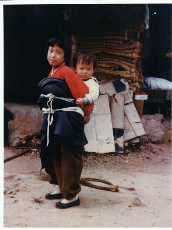 An older sister carrying her younger brother in Sambatt Village in 1954.